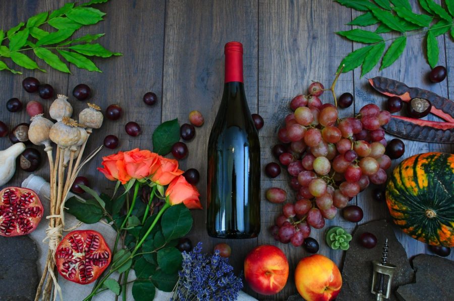 No label on wine bottle in center of table surrounded by fruit.