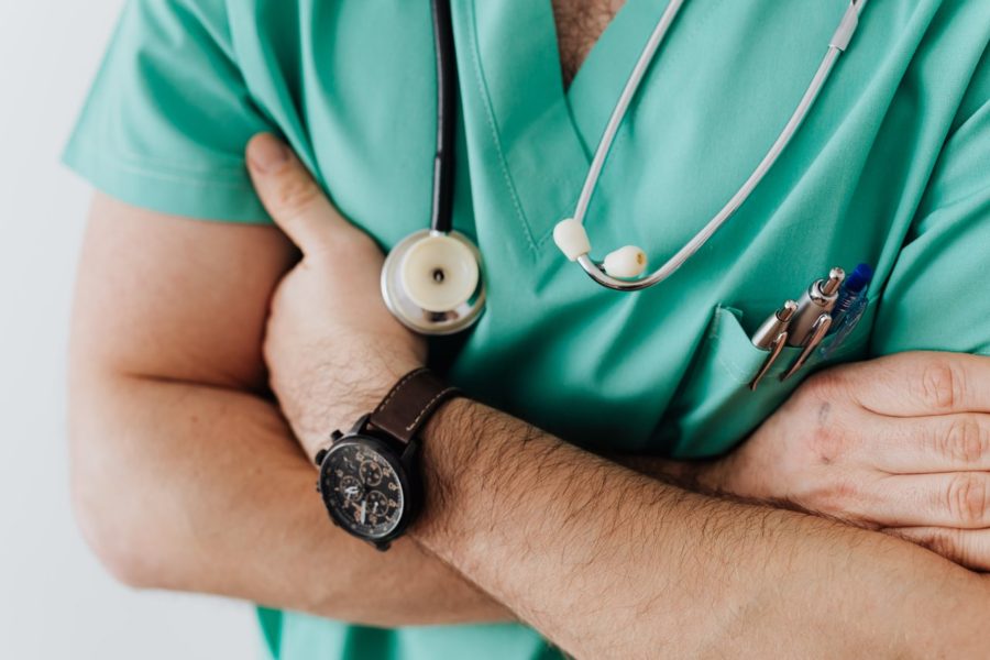 Male doctor in scrubs with arms crossed.