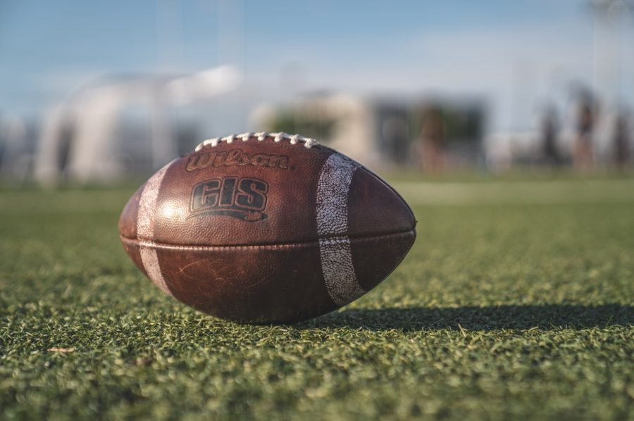 Football sitting in the middle of a green football field.