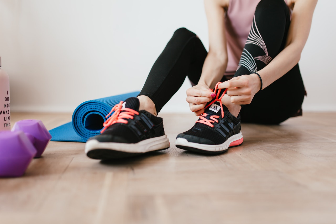 Woman tying her workout shoes inside.