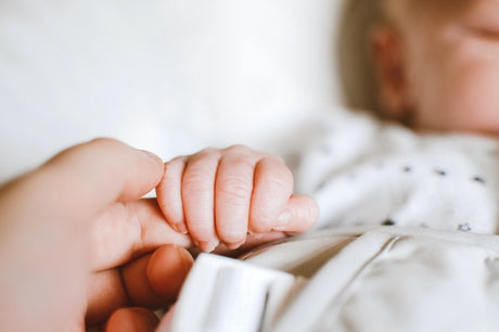 Newborn baby holding parent's finger.