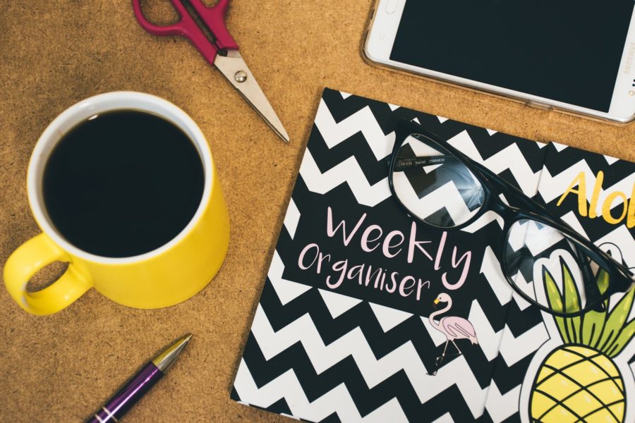 Weekly organizer with coffee mug and pen.