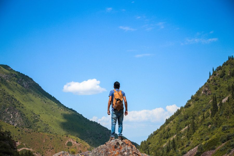 man standing on rock facing mountains