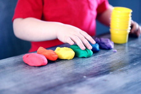 Kid playing with colorful playdough at home.