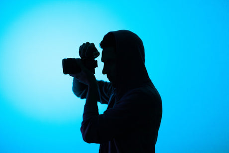 Man holding canon camera in front of blue background