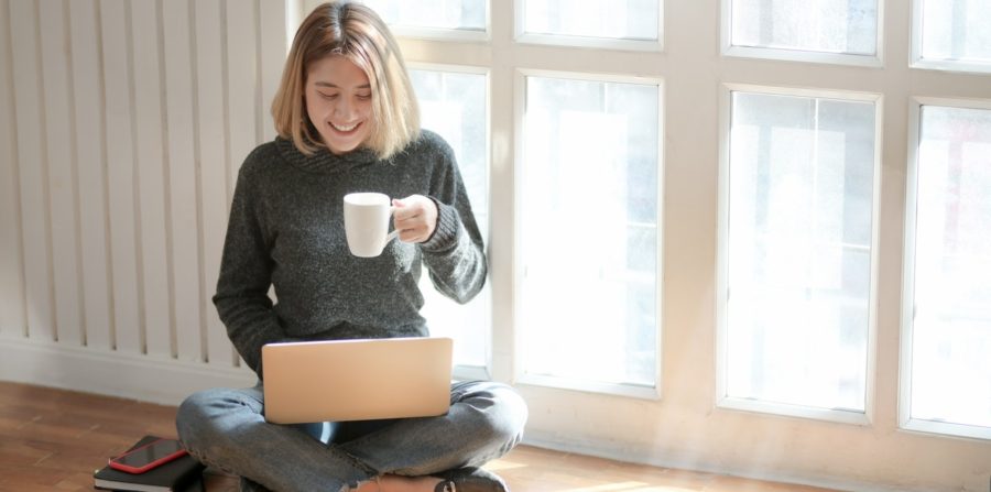 woman drinking coffee and looking at laptop