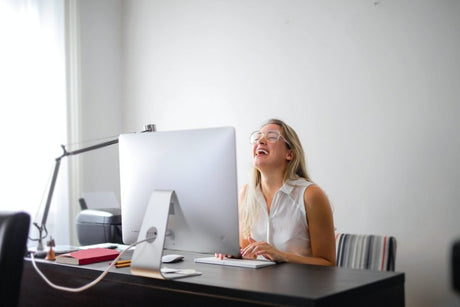 woman in front of monitor laughing at screen.